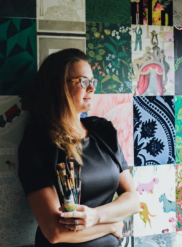 Emily K. Joynt holding paintbrushes in her studio
